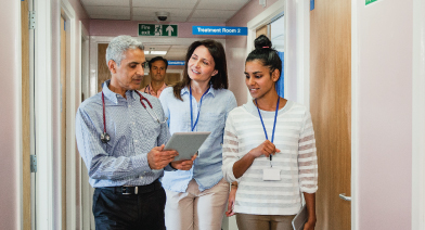 Clinic staff walking down the hall looking at a chart